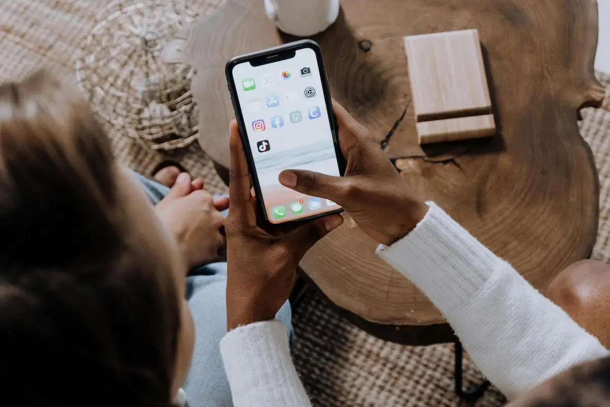 A person holding a smartphone looking at home screen