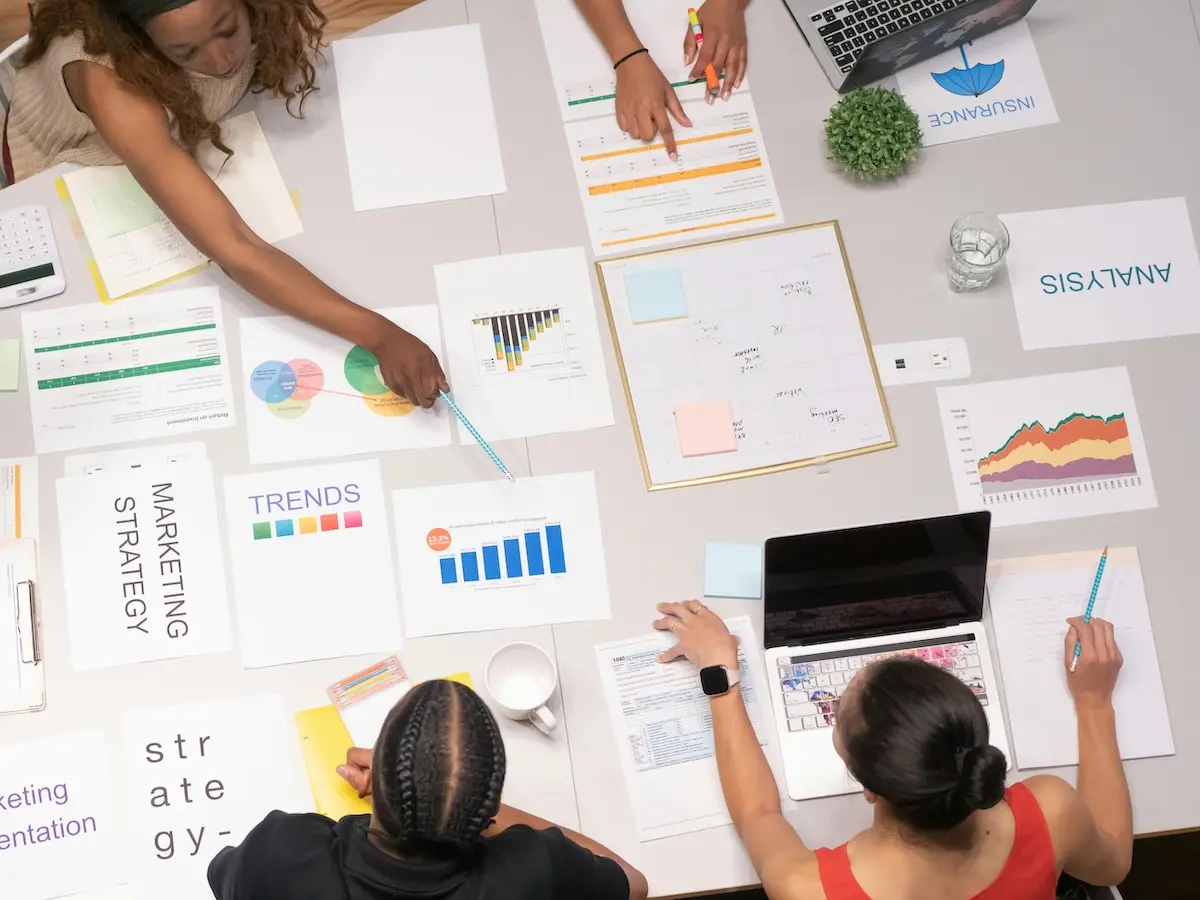 People discussing multiple graphs spread-out on a table in front of them in a business setting