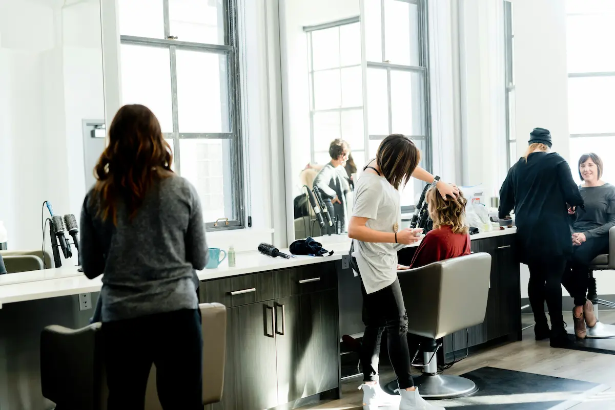 Pracownicy salonu fryzjerskiego pracujący nad klientamiś