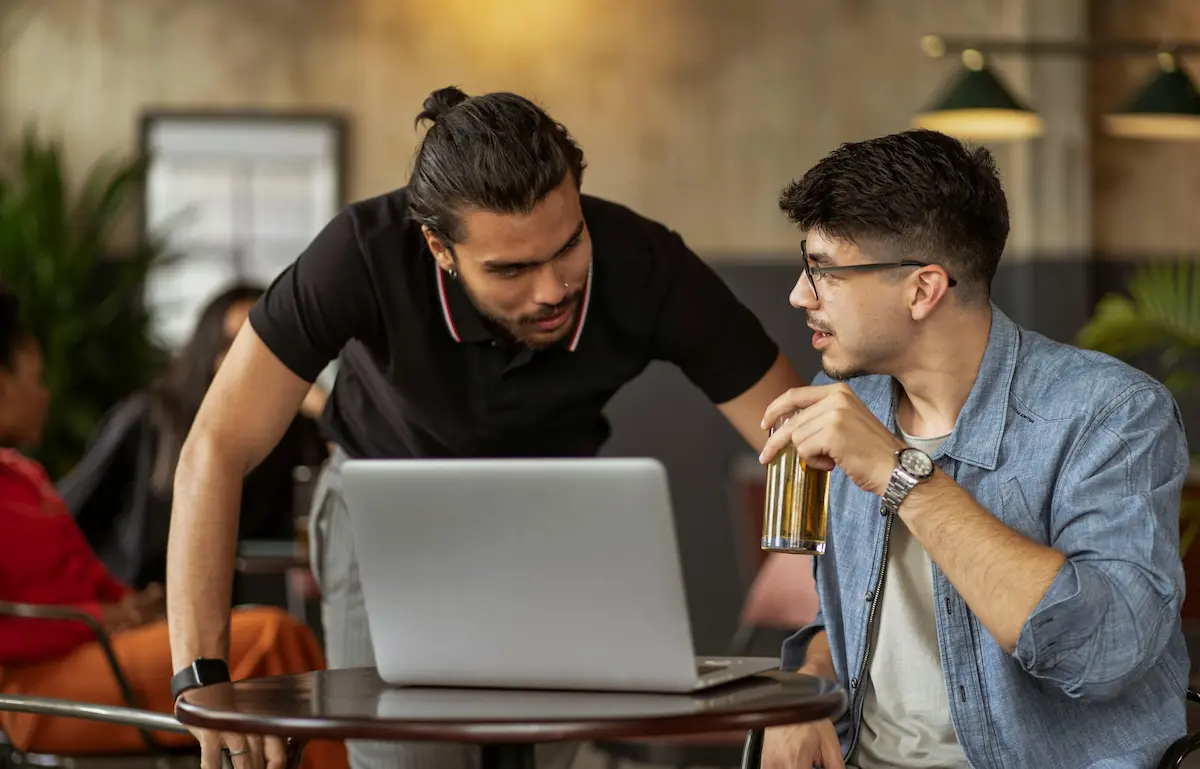 Dwóch męzczyzn rozmawiających przed laptopem w restauracji